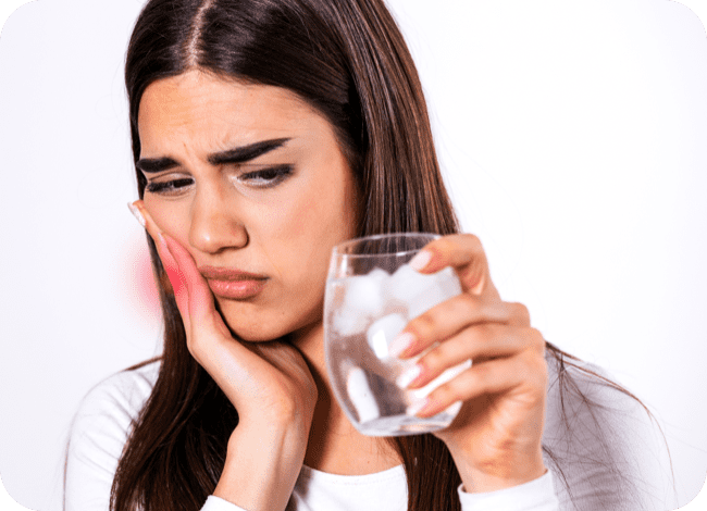 ragazza che beve un bicchiere di acqua fredda e ha male ai denti 